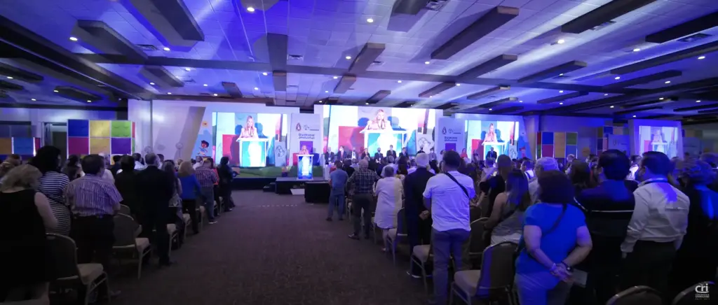 Salón con escenografía y pantallas para conferencia ante público