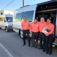 Equipo de CRI Tours uniformado junto a unidad de transporte